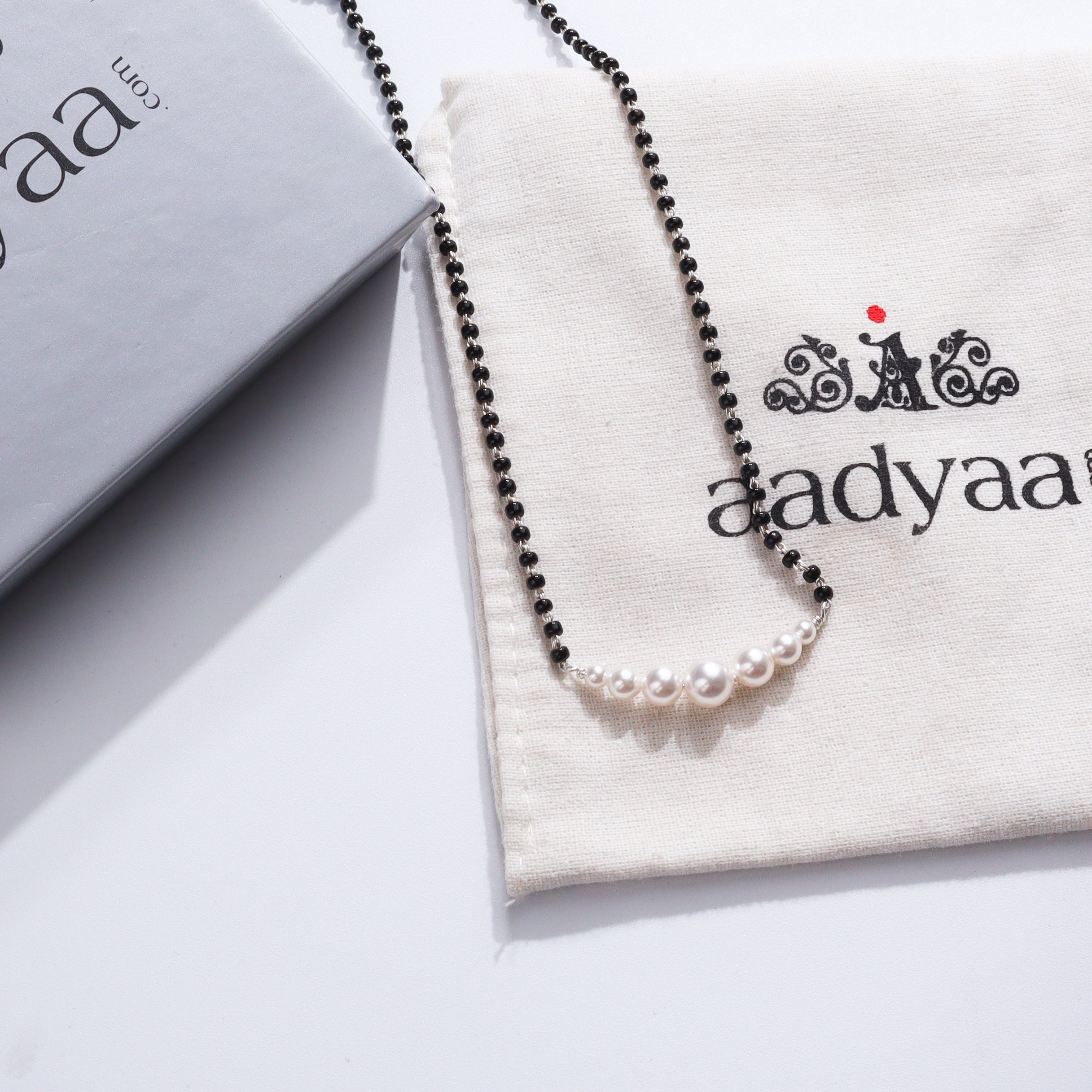 Minimal Pearls Silver Mangalsutra with black beads and white pearls on a jewelry pouch