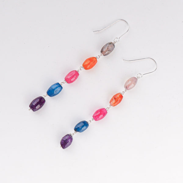 Close-up of multicolour dangling earrings highlighting handcrafted settings and colorful gemstone detailing
