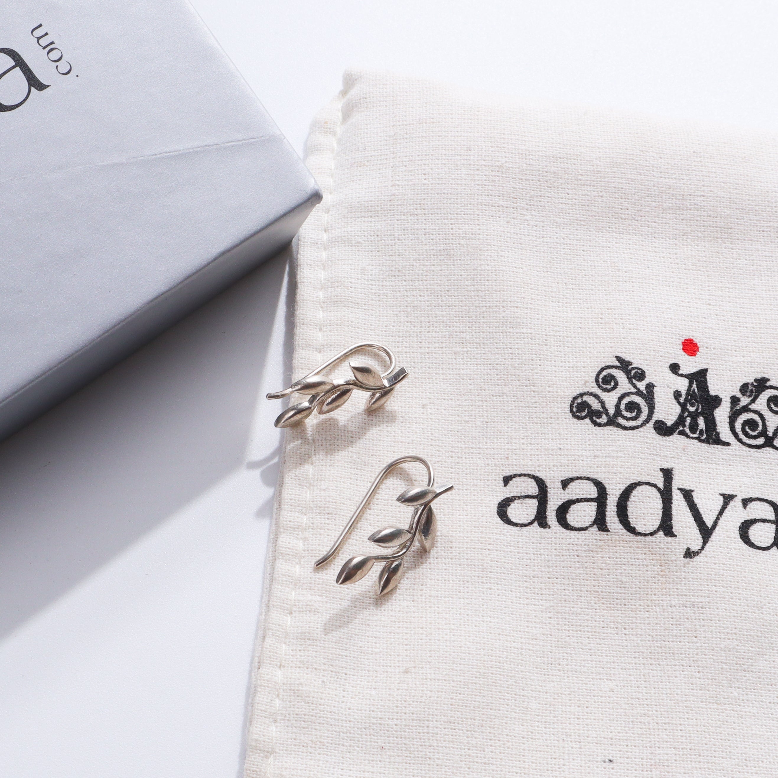 Silver Leaf Earcuffs earrings on fabric with packaging