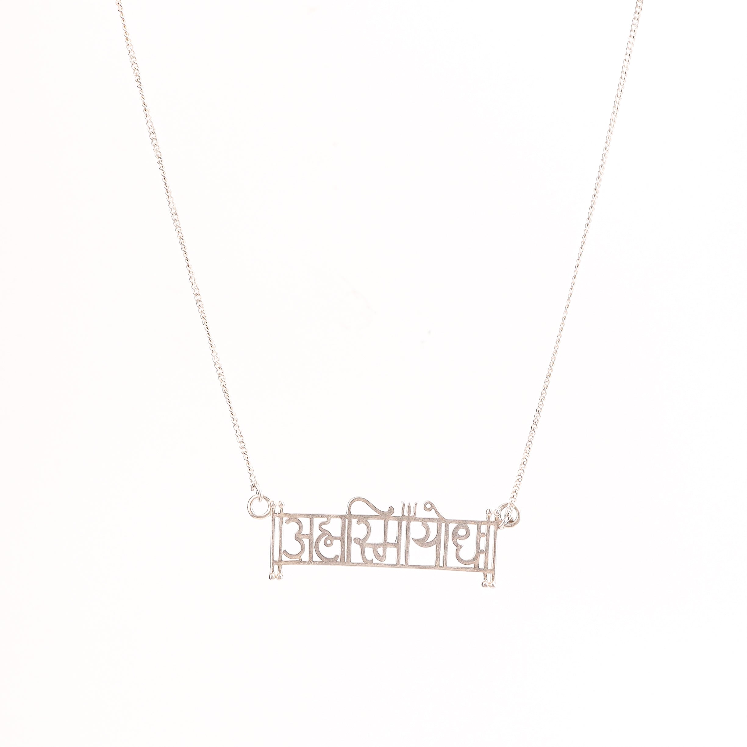 Flat-lay Ahamsmiyoddha laser cut silver necklace on neutral background
