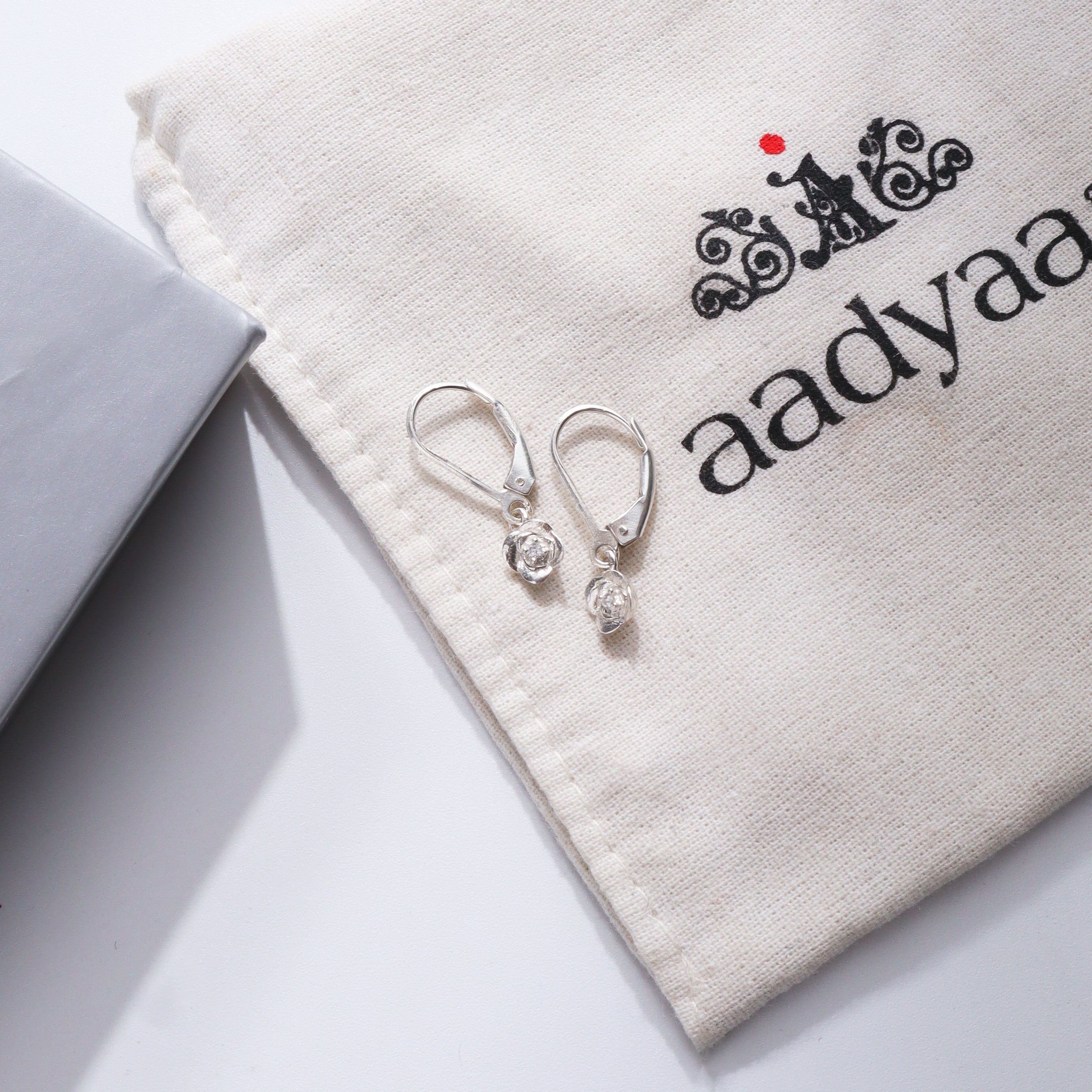 Rose CZ earrings in silver on Aadyaa jewelry pouch