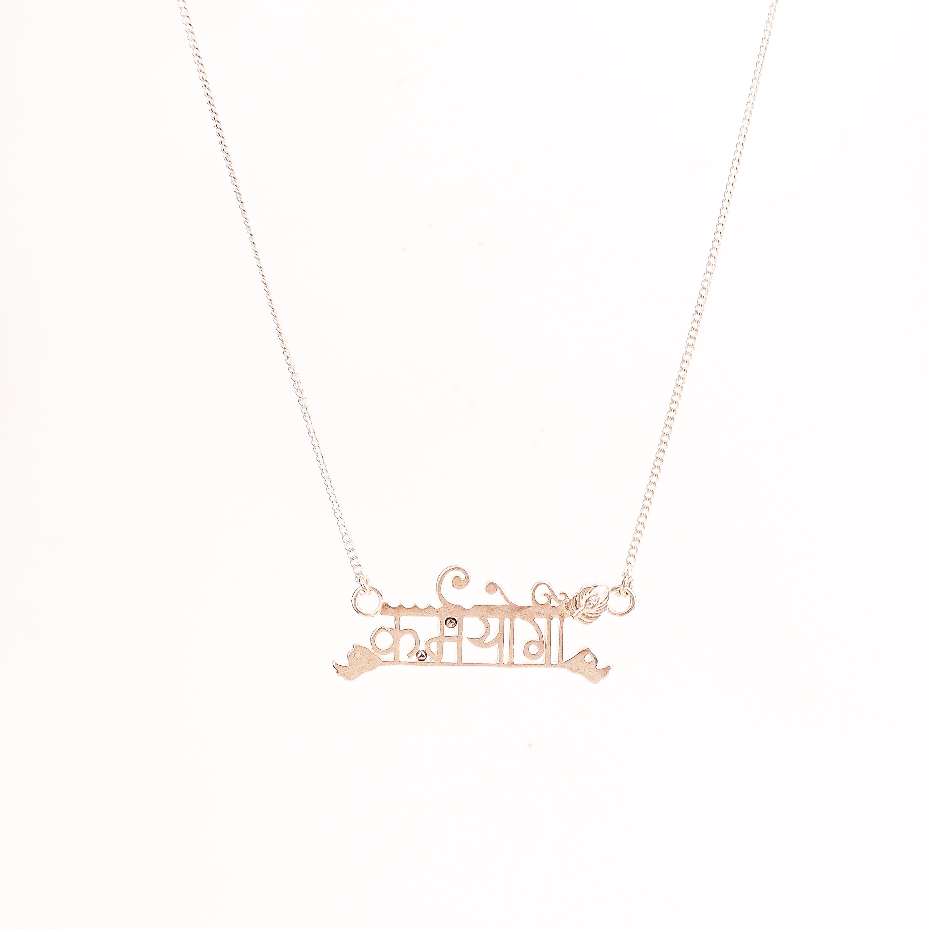 Flat-lay Karmayogi silver necklace on neutral background