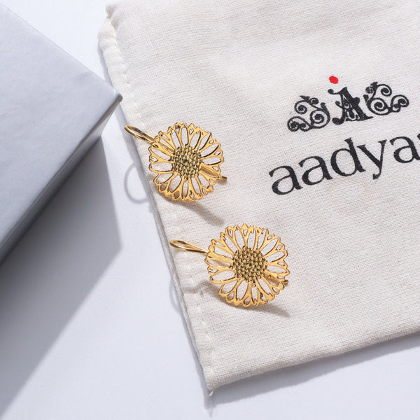 Gold floral earrings on white fabric with black text