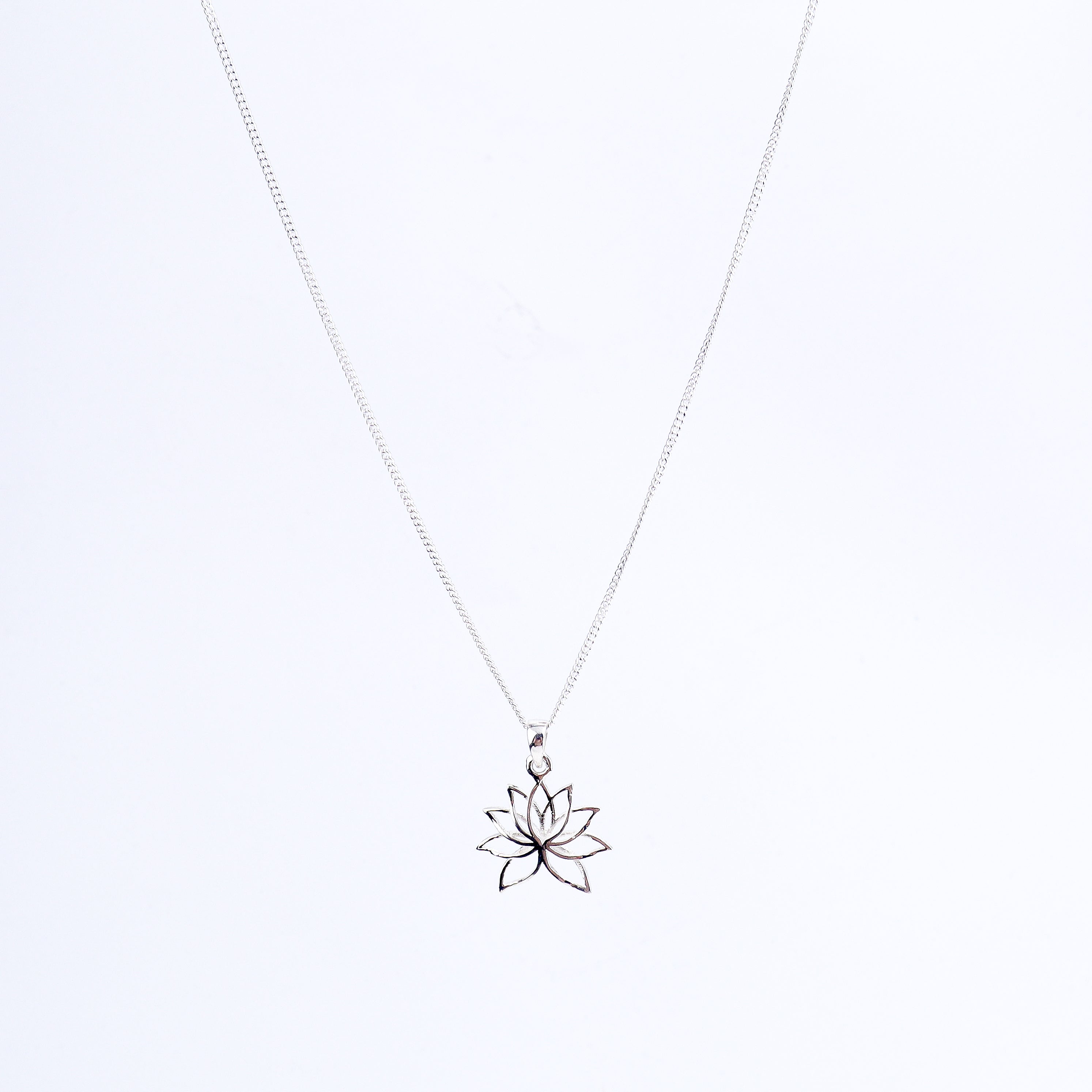 Flat-lay lotus charm silver necklace on neutral background