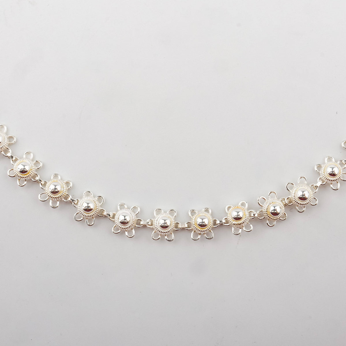 Close-up of silver chain clasp and floral charm jewelry