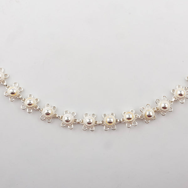 Close-up of silver chain clasp and floral charm jewelry