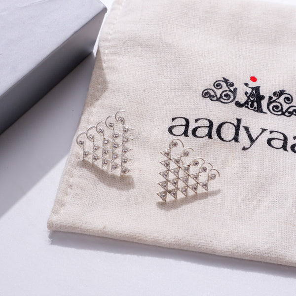 Silver earrings with small motifs on beige fabric