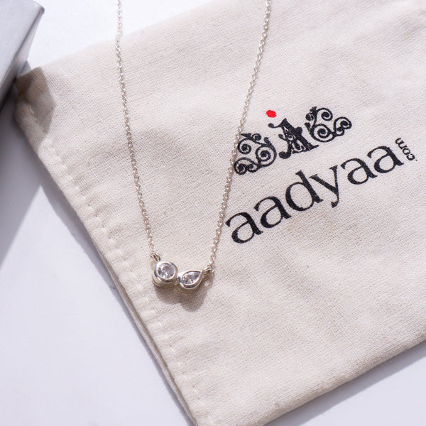 Silver chain with twin CZ dots on beige fabric