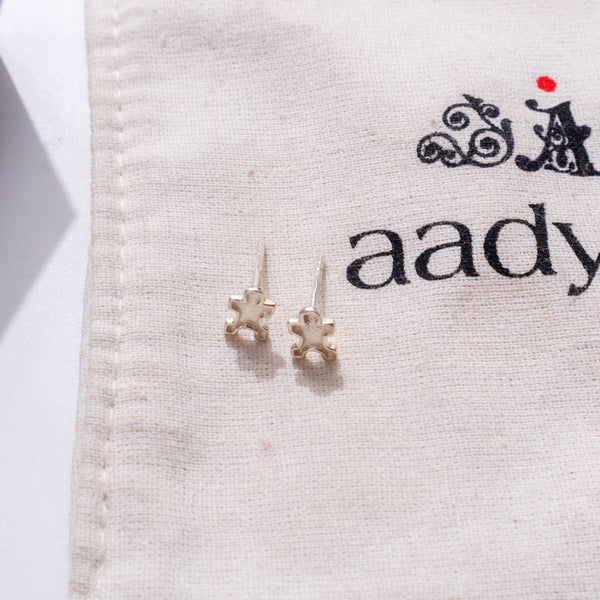 Silver jigsaw puzzle earrings on fabric