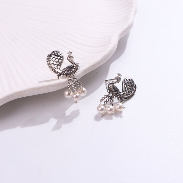 Silver peacock earrings with pearls on white background