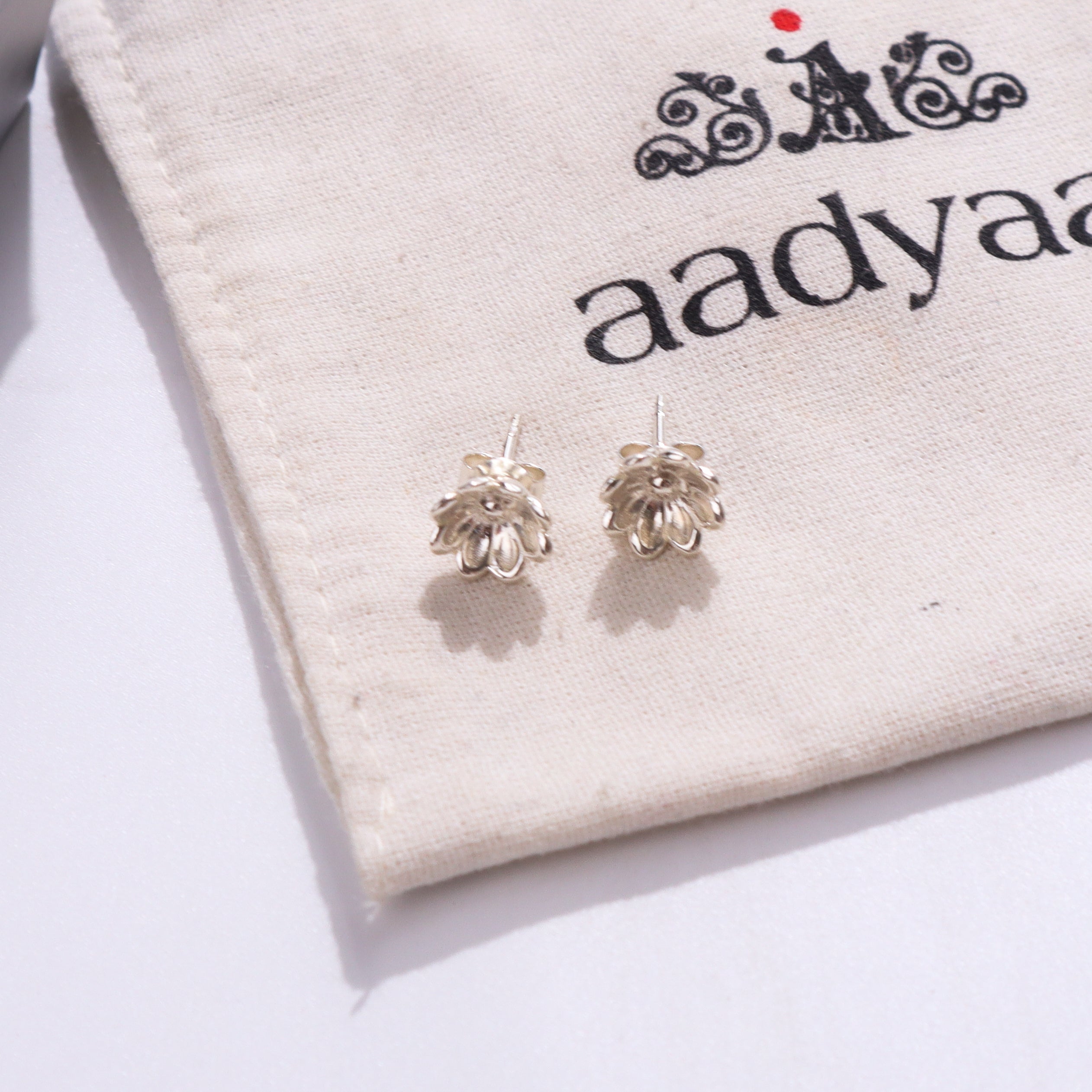 Silver flower earrings on beige fabric