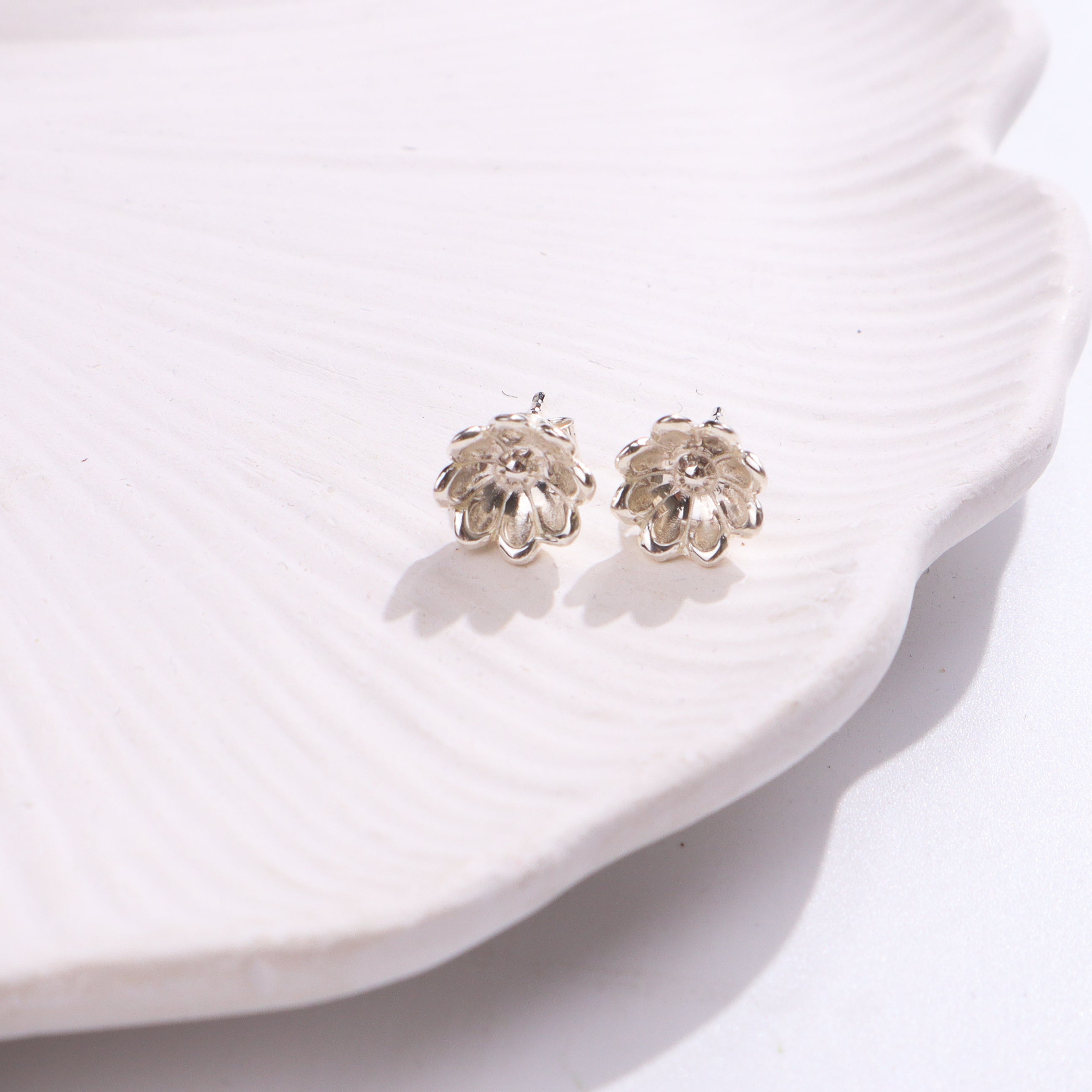 Silver flower stud earrings on white background