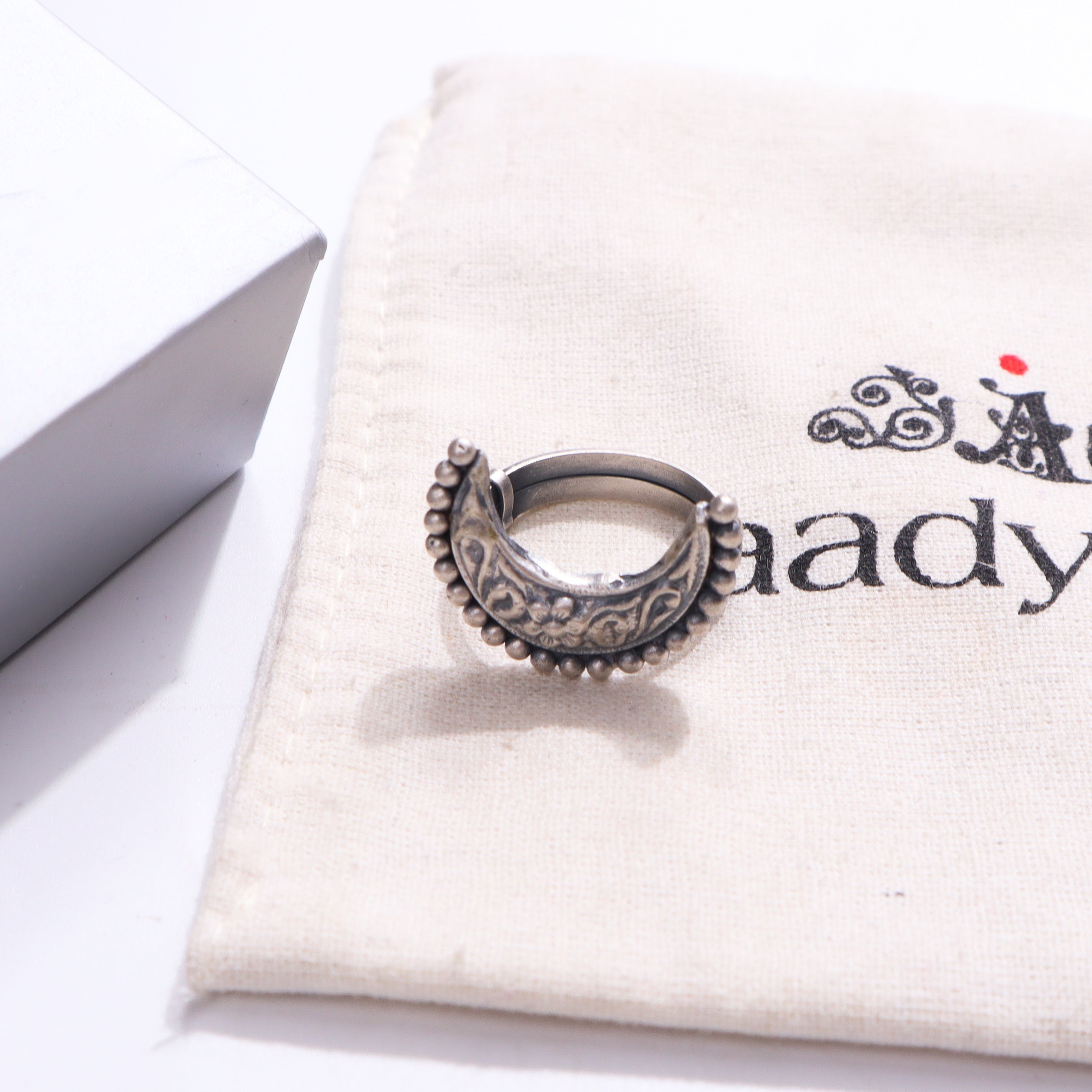Silver ring with intricate design on white fabric