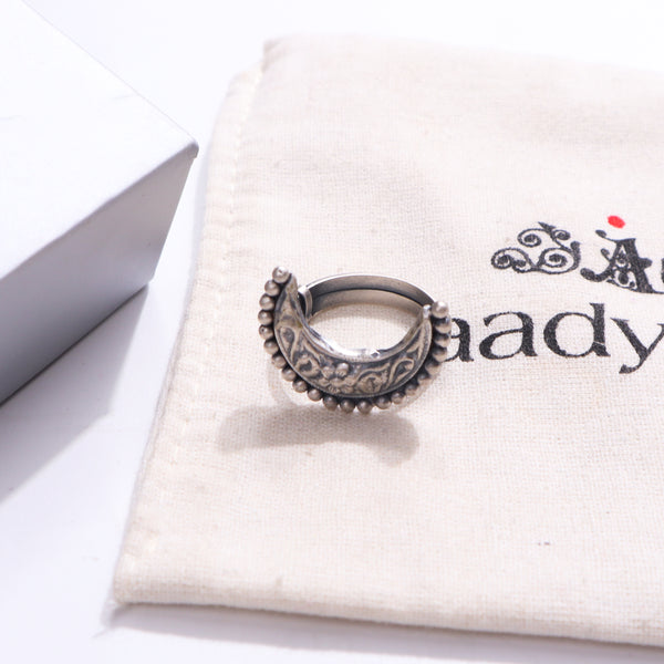Silver ring with intricate design on white fabric