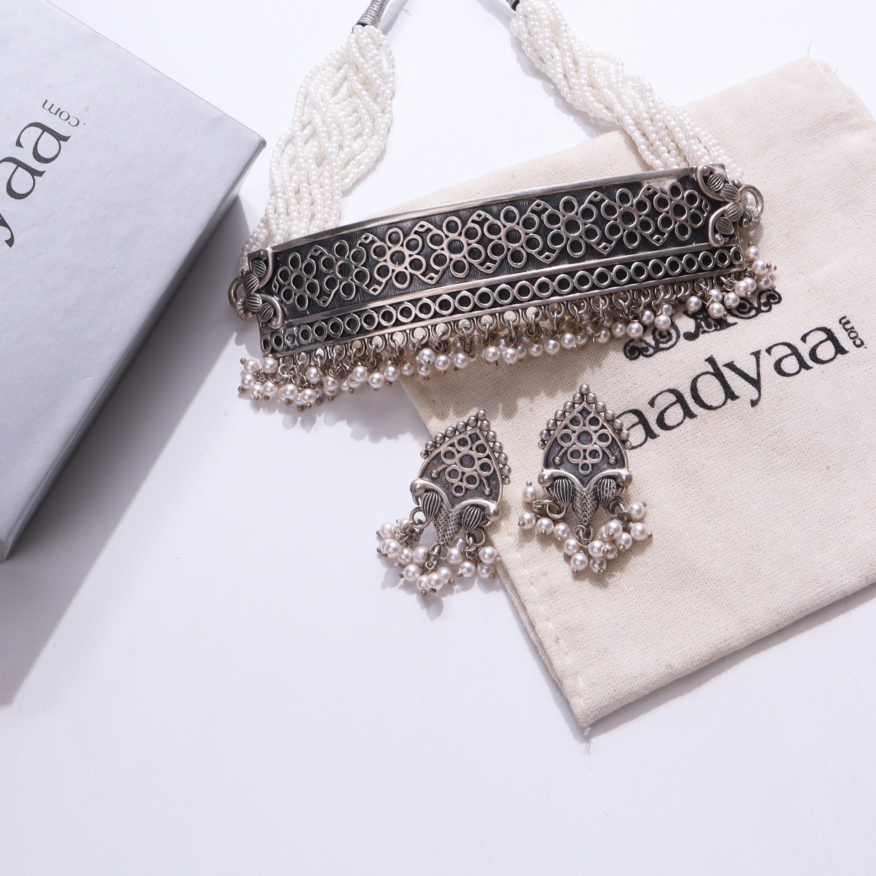Sterling silver choker set with pearl accents on beige fabric