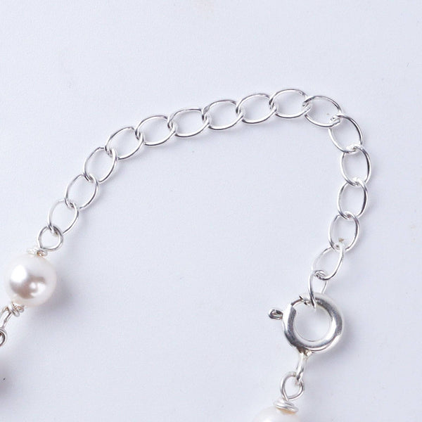 Flat-lay of silver pearl Ganthan necklace with multicolor stones on silk fabric with soft lighting