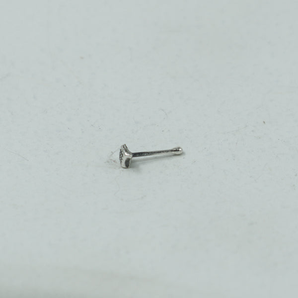 Close-up of silver dotted diamond nose pin on white surface