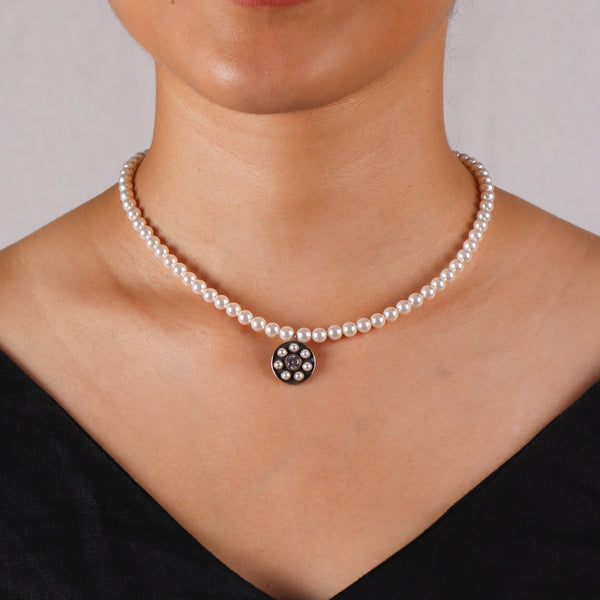 Woman wearing pearl necklace with silver pendant, stylish jewelry accessory