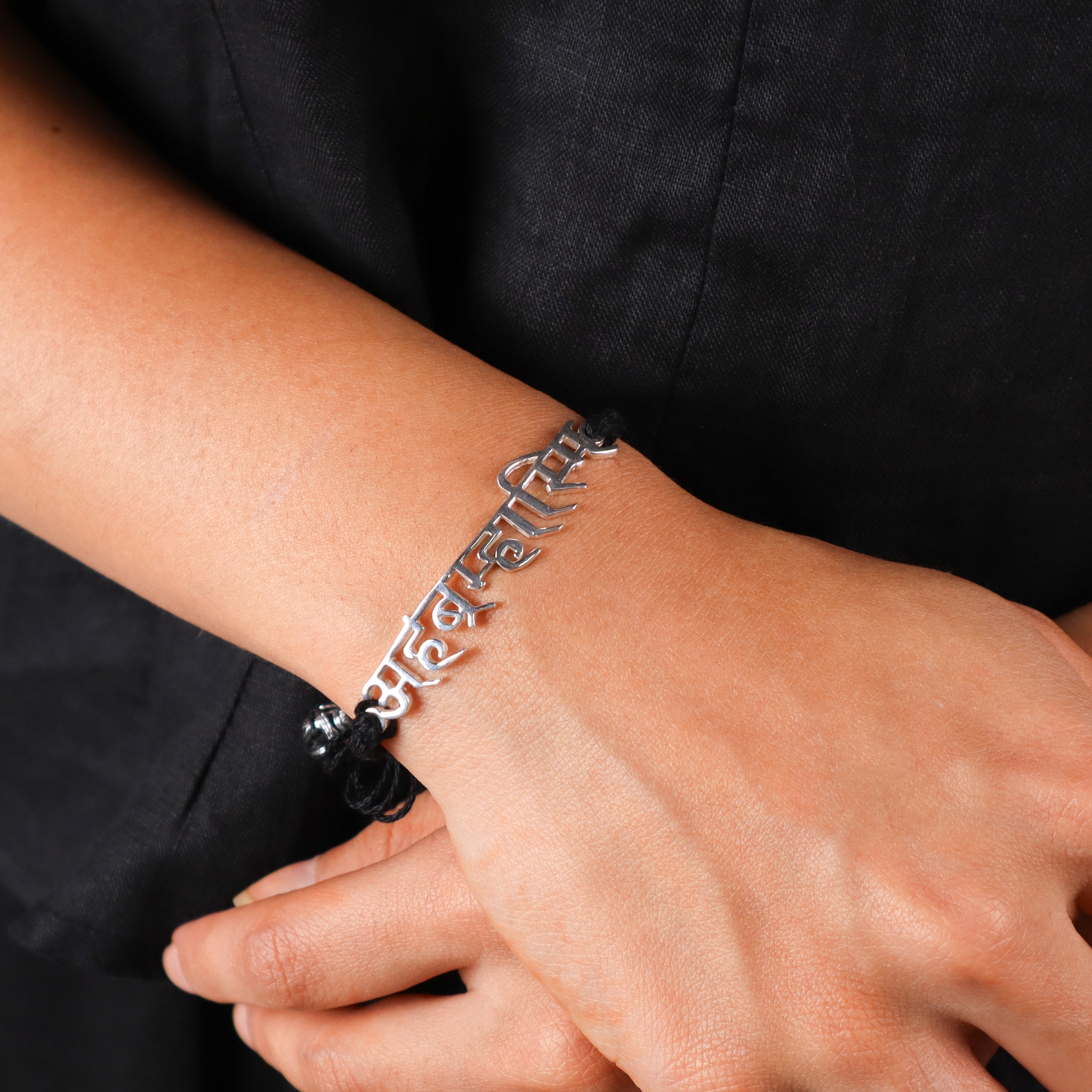 Close-up of silver Sanskrit inscription bracelet on wrist, spiritual jewelry