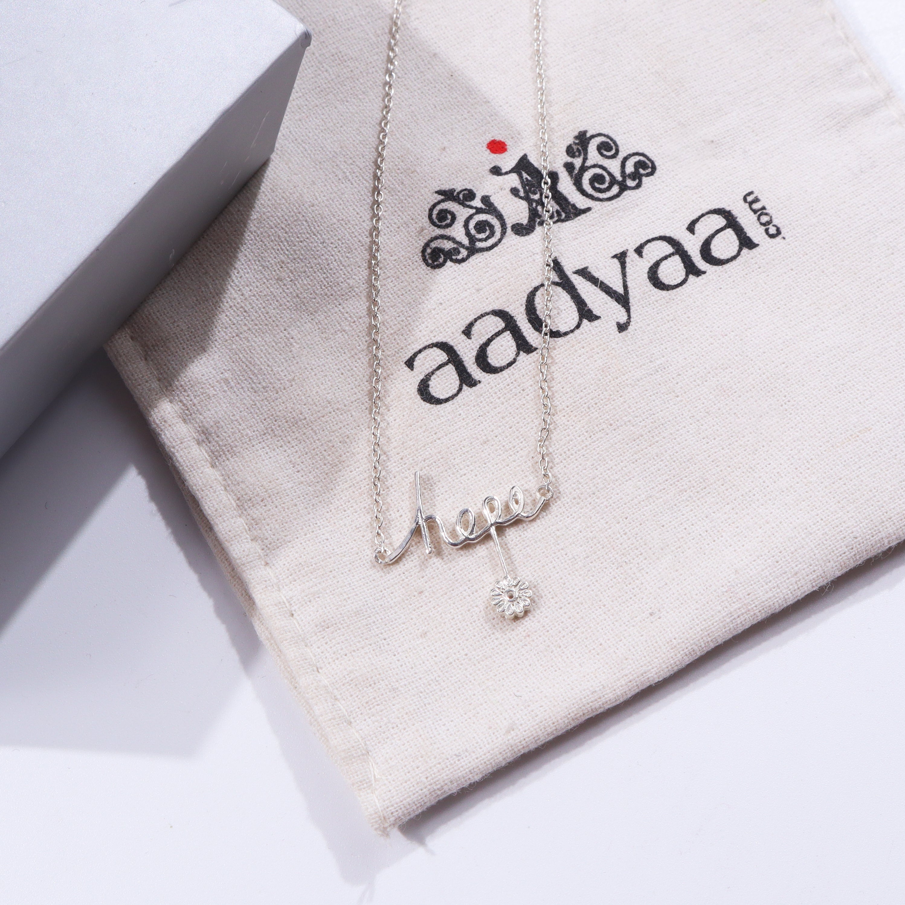 Silver Hope Pendant Necklace on beige fabric with House of Aadyaa logo