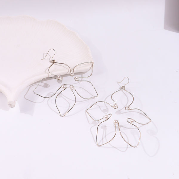 Silver pearl flower earrings on white shell