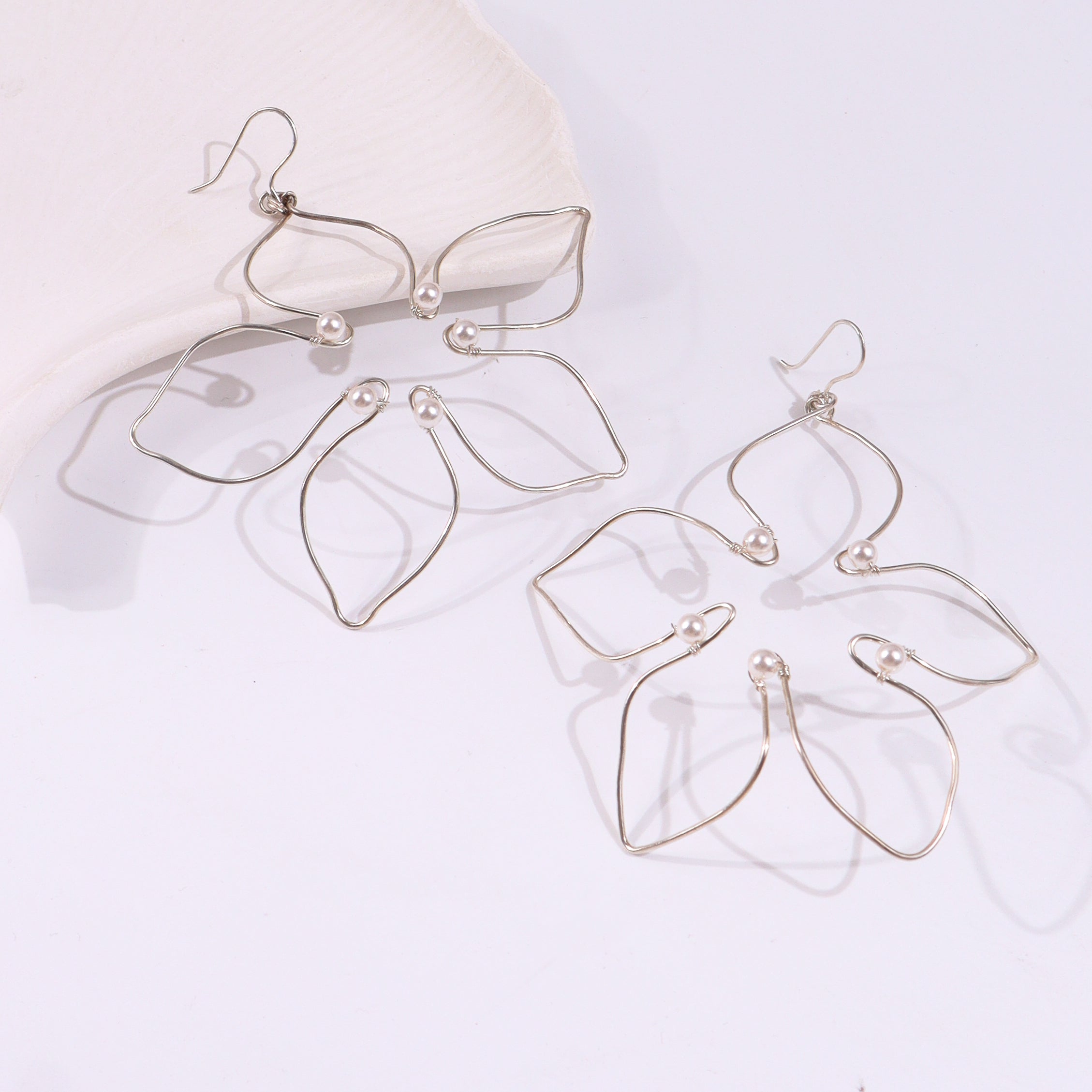 Silver wire earrings with pearl accents on white background