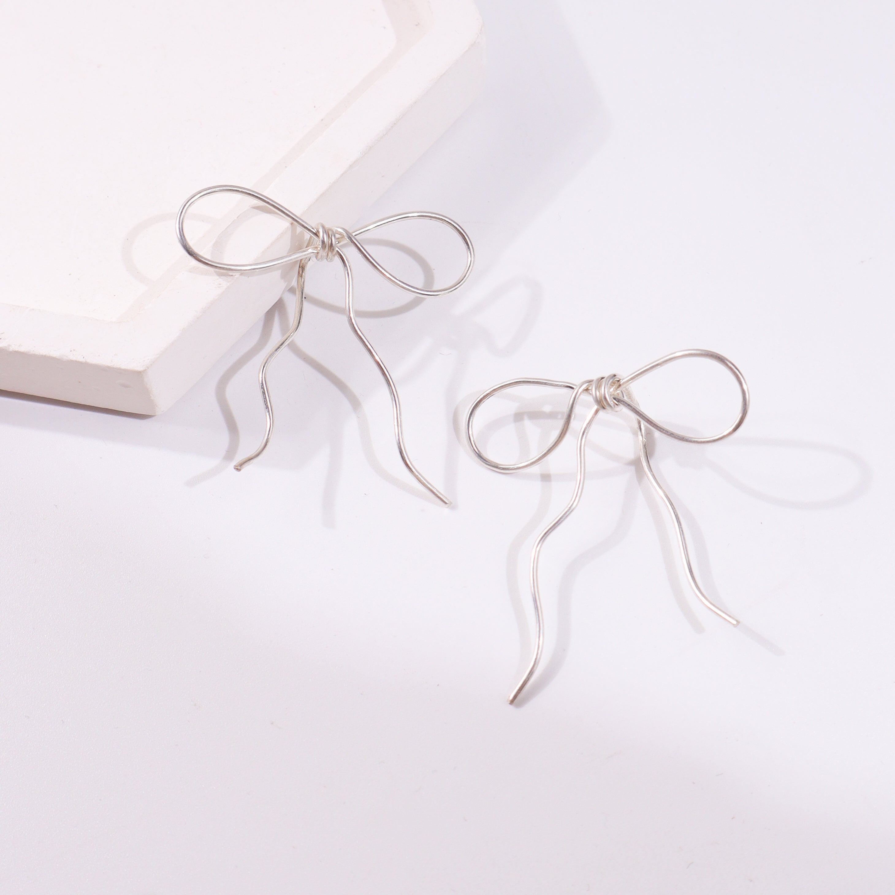 Silver bow earring on white background