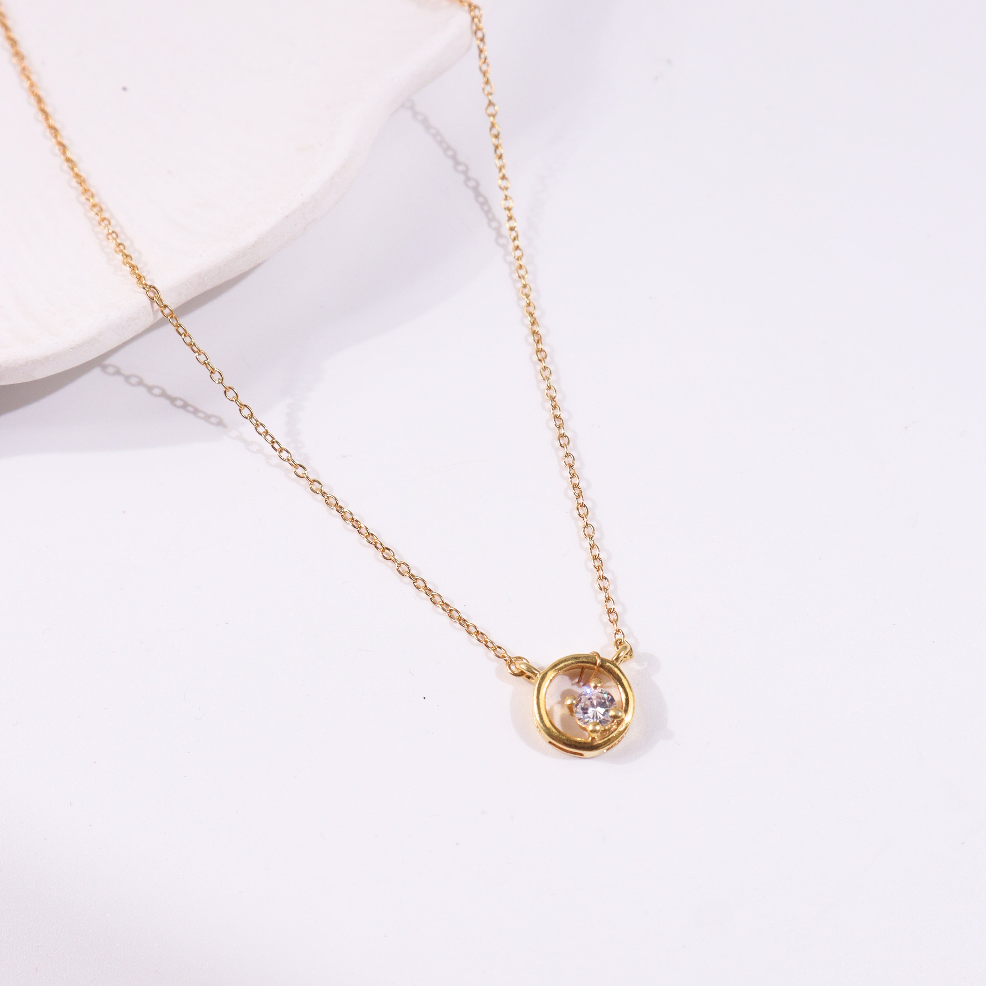 Gold chain with circular pendant and gemstone