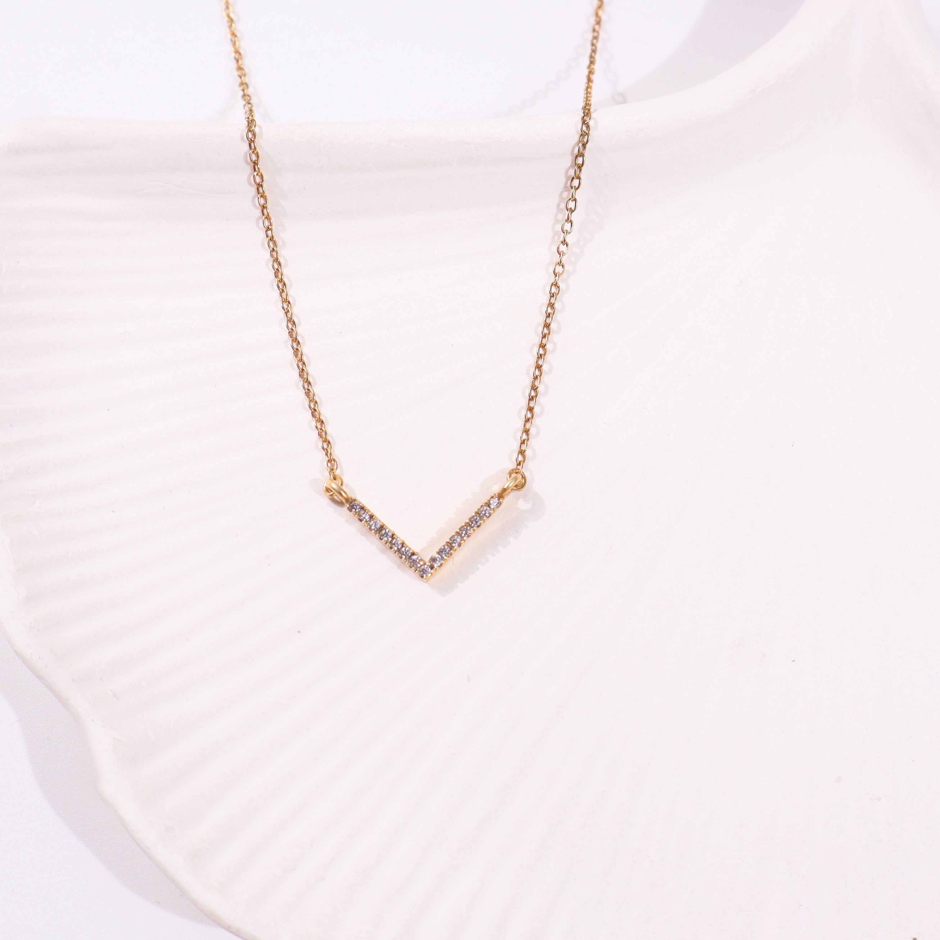 Gold V-shaped necklace with CZ stones on white background