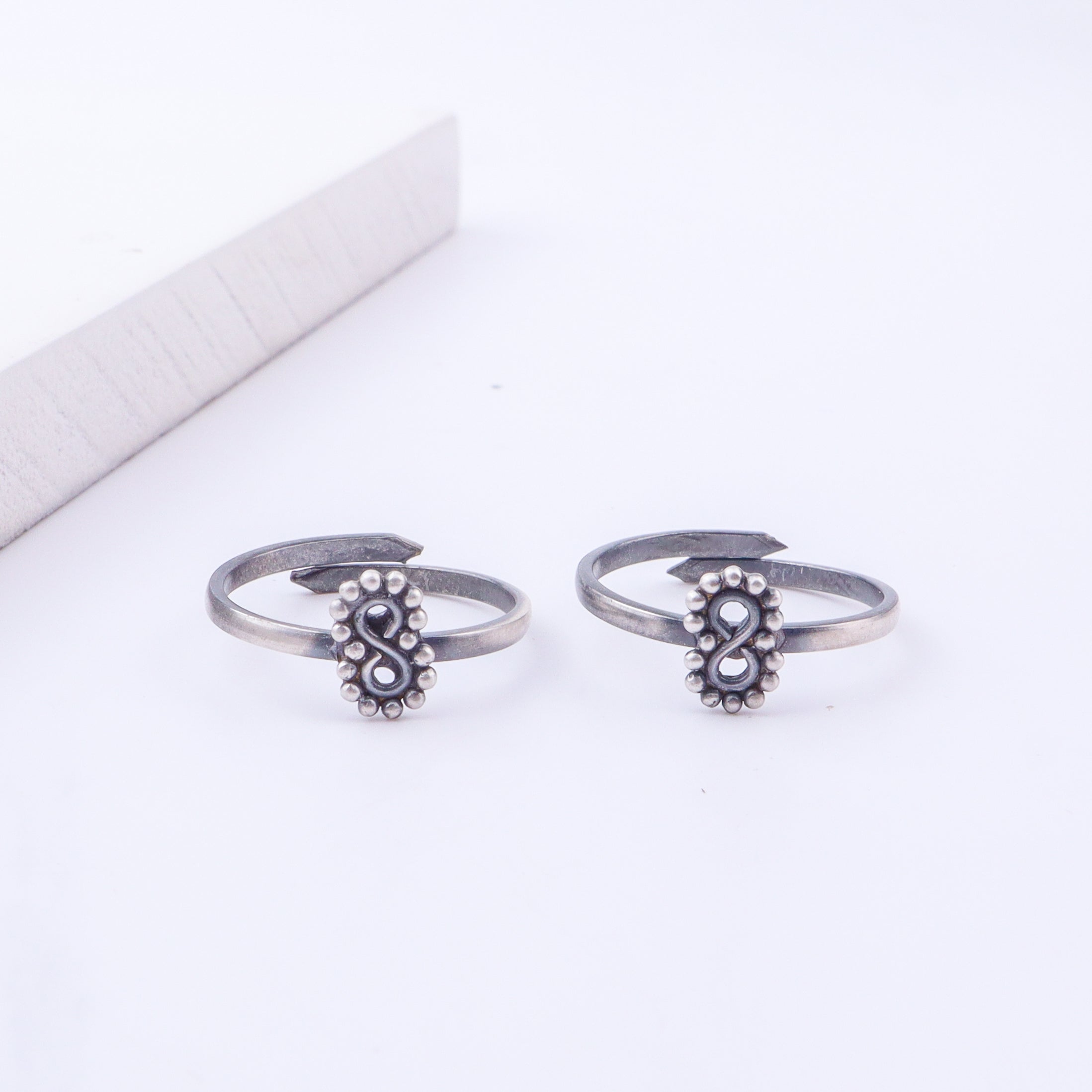 Model wearing tiny silver adjustable infinity toe ring