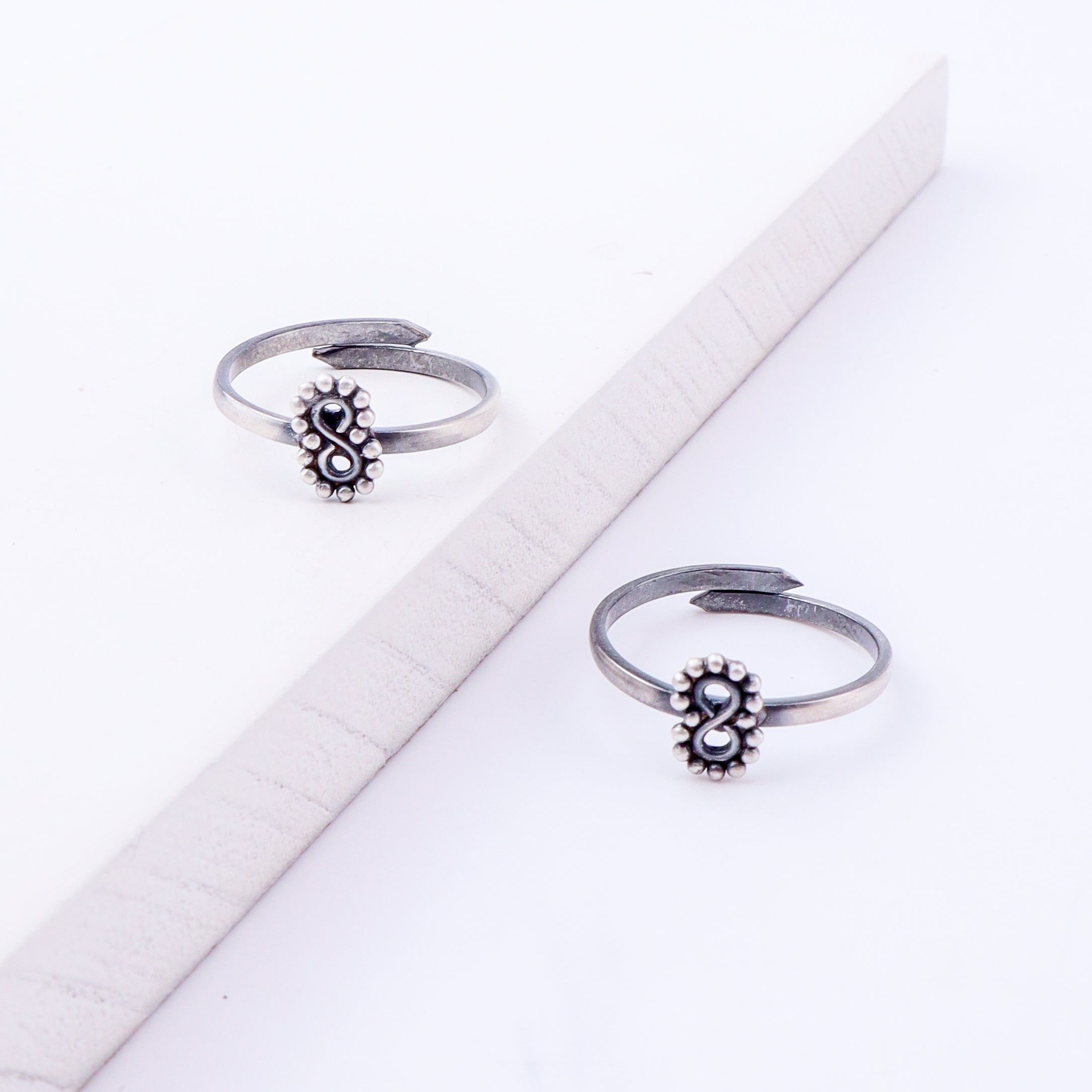 Angled view of tiny infinity silver toe ring adjustable