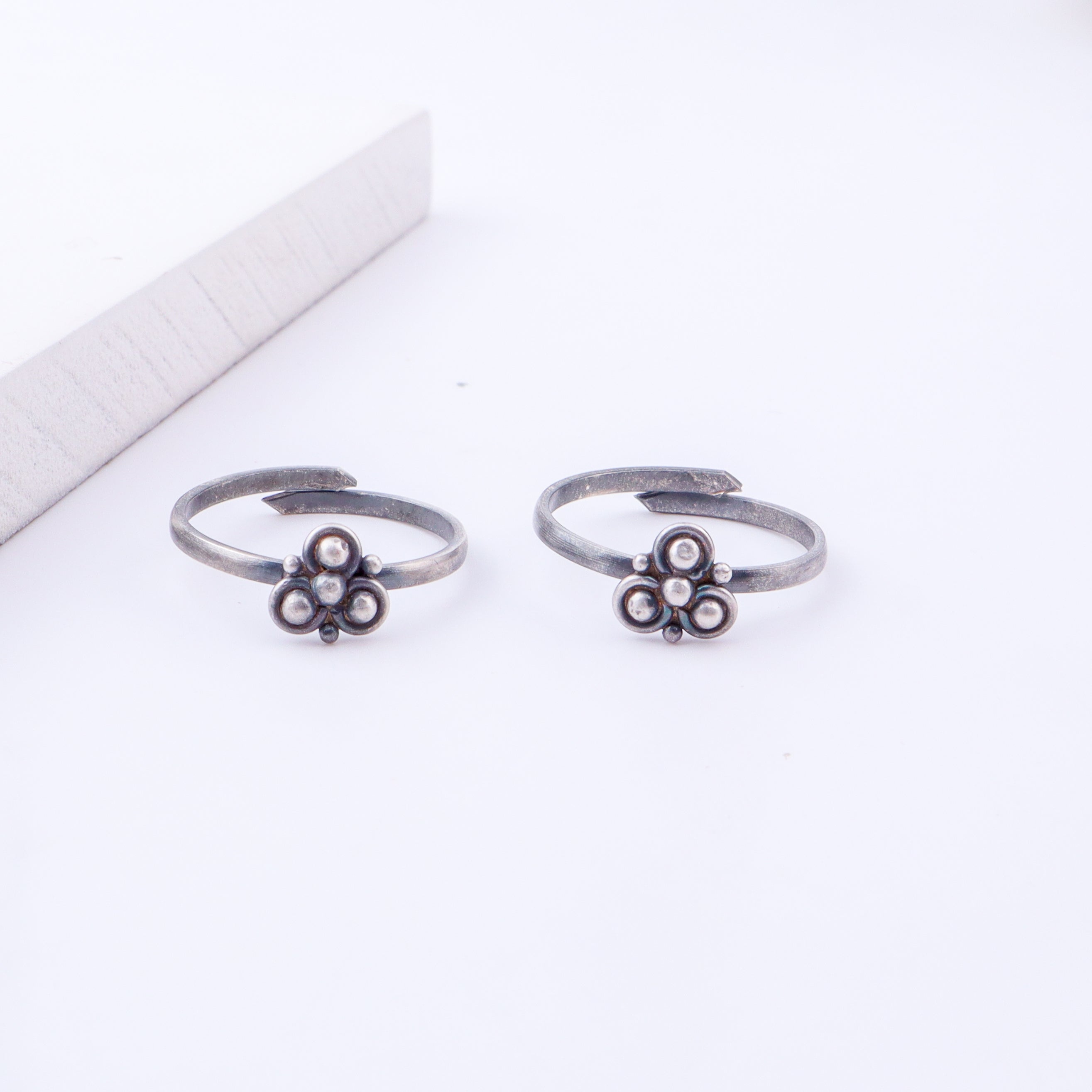 Detail shot highlighting polished silver floral design and open band