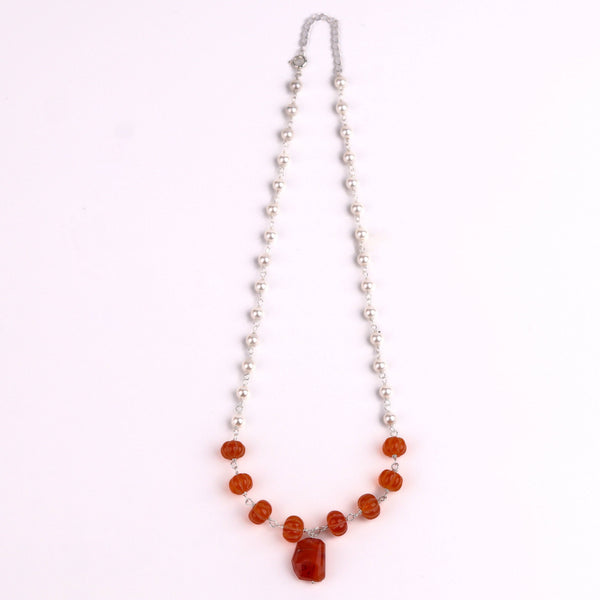 Flat-lay of pearl Ganthan necklace with semiprecious stones on silk fabric with soft natural light