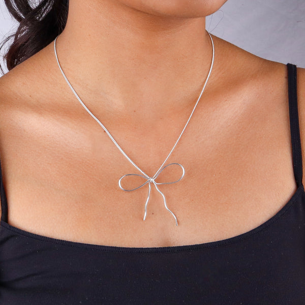 Silver bow necklace on woman's neck