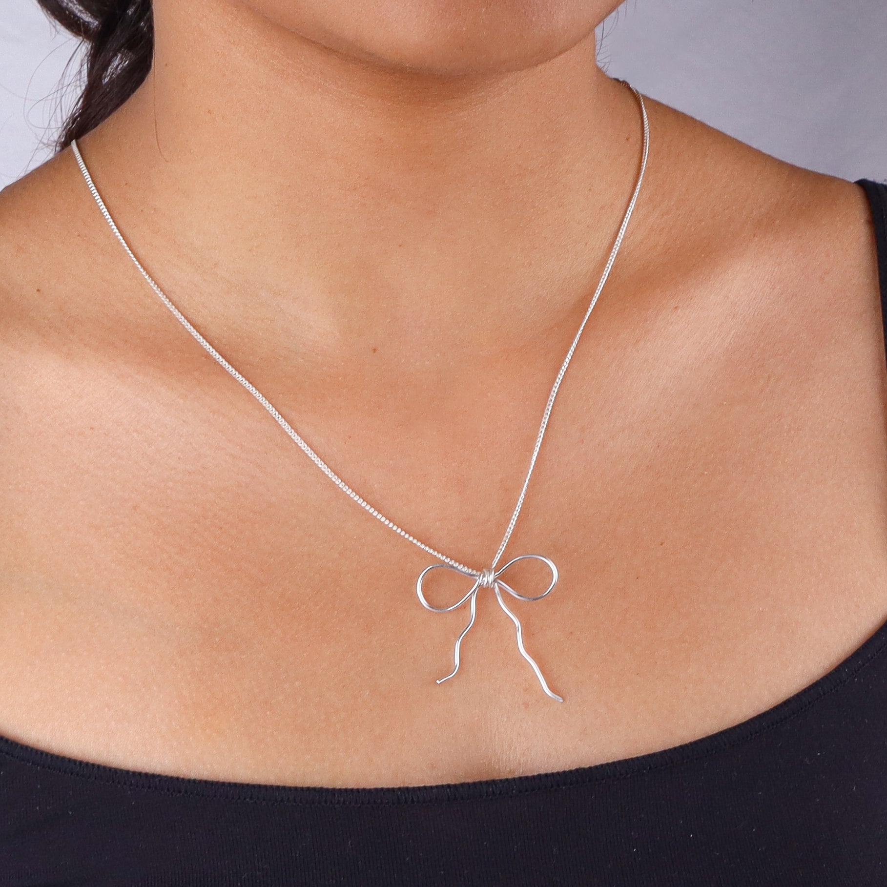 Silver bow necklace on woman's neck
