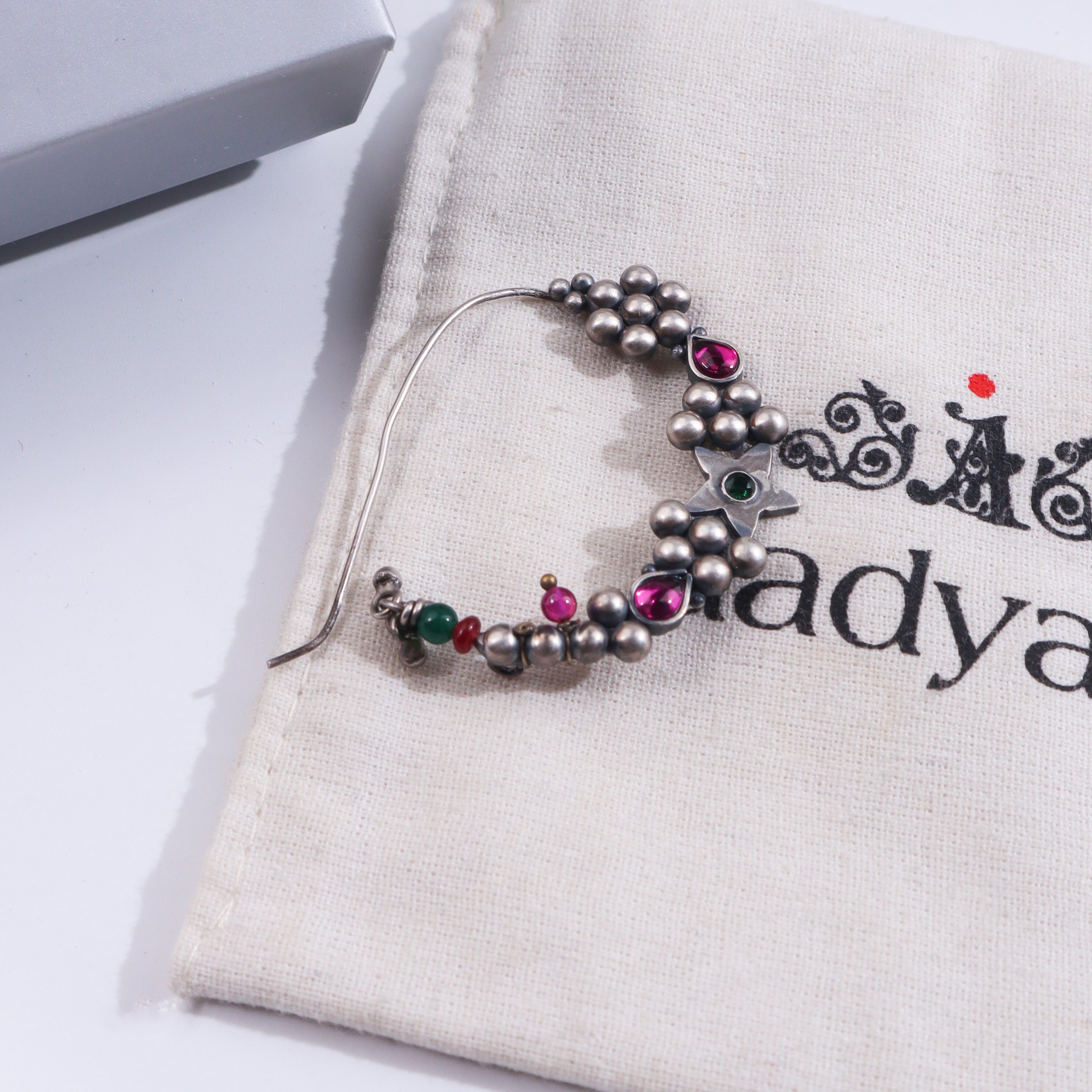 Silver Indrayani Nath with pink gemstone on beige fabric