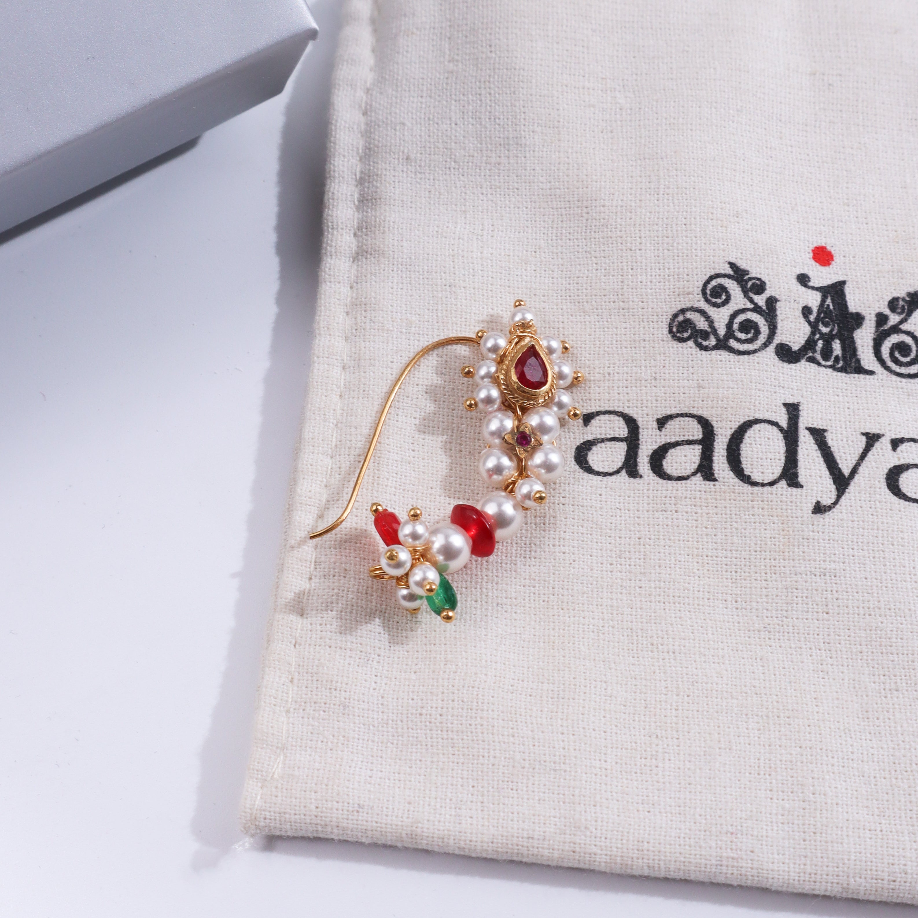 Close-up of pearl and ruby nose ring on white background