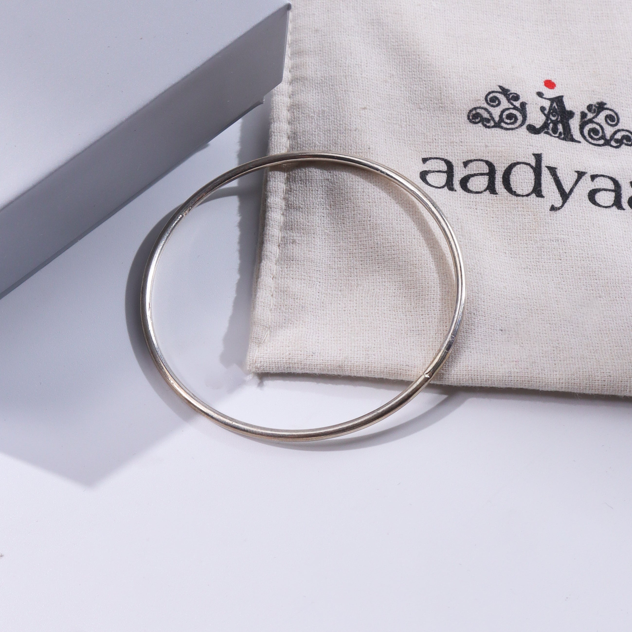 Silver bangle on white background with fabric pouch