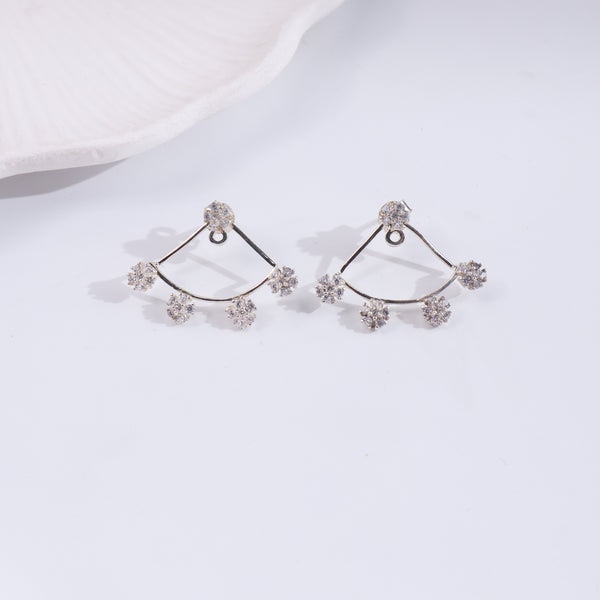 Silver flower CZ earrings on white fabric, detailed close-up