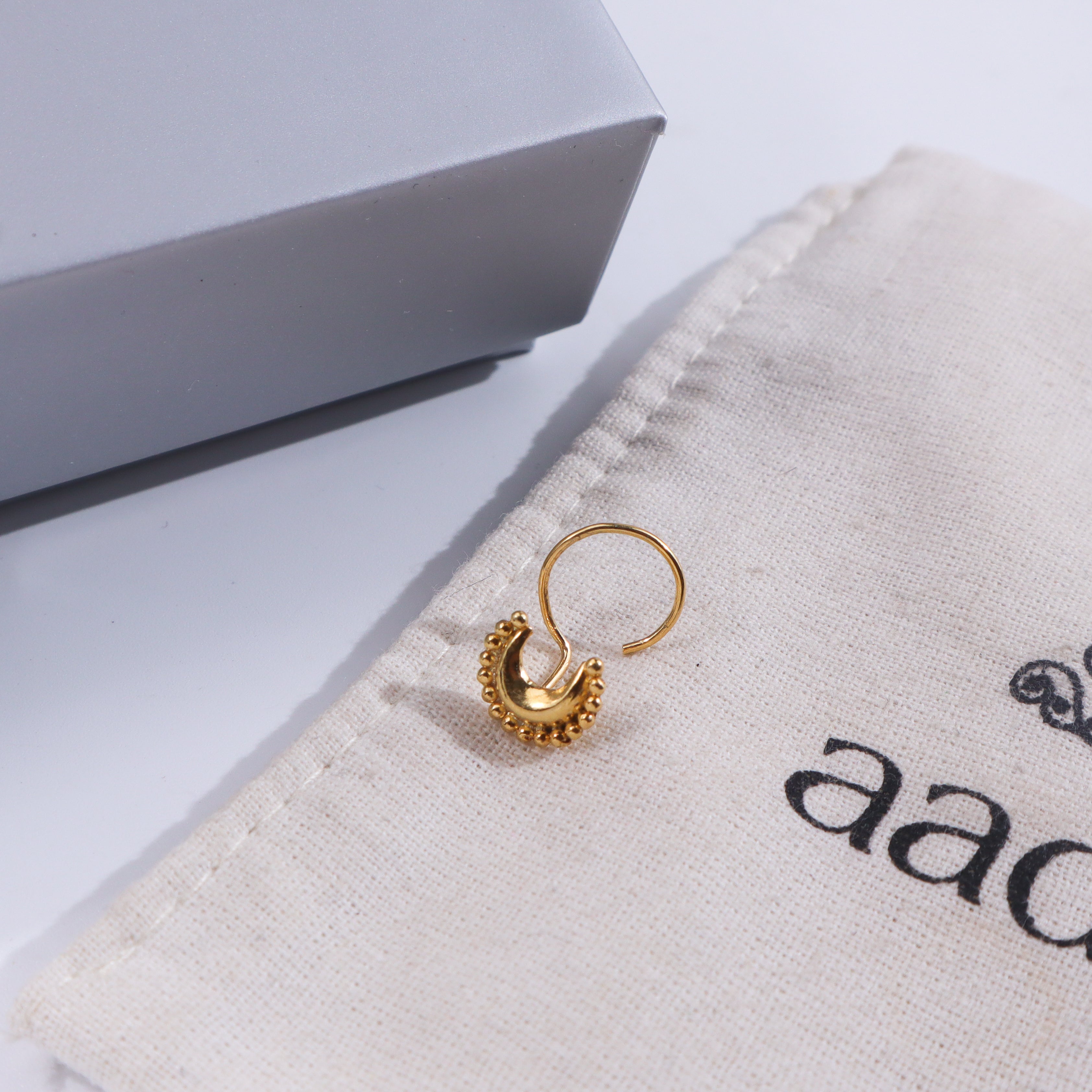 Gold-plated crescent moon nose pin on fabric