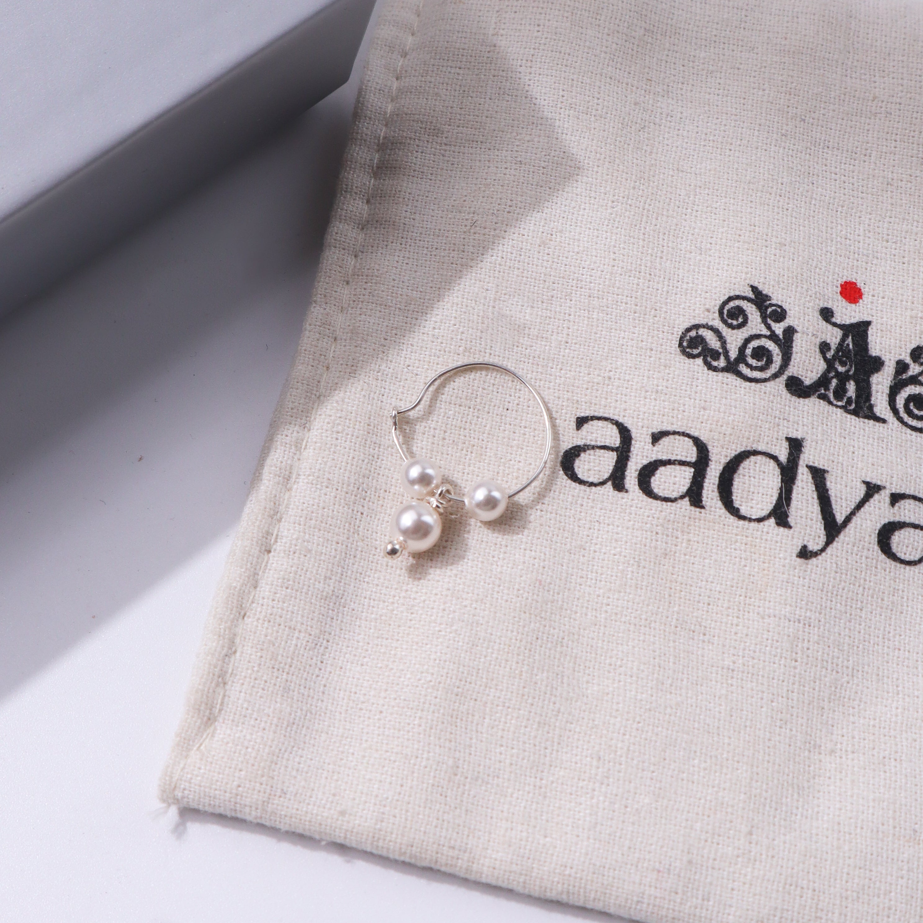 Pearl hoop earring with silver accents on beige fabric