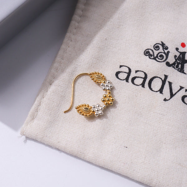 Gold nose ring with pearl embellishments on beige fabric