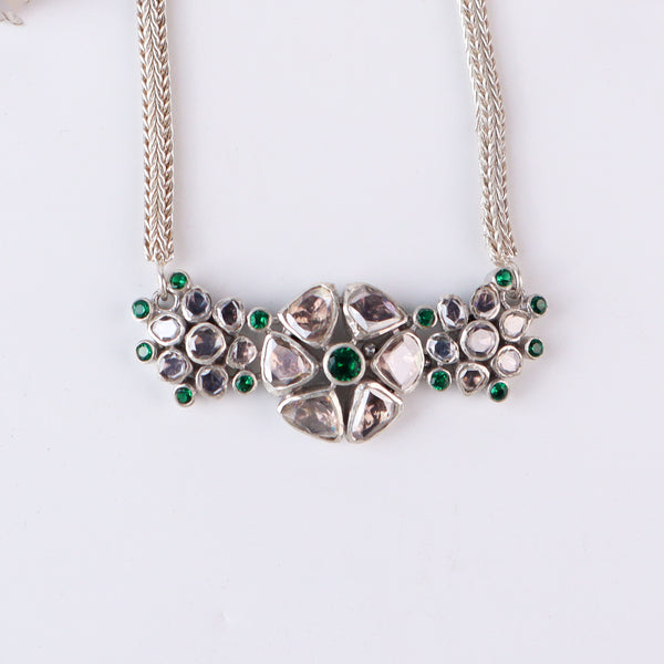 Close-up of silver necklace with green stones and chain
