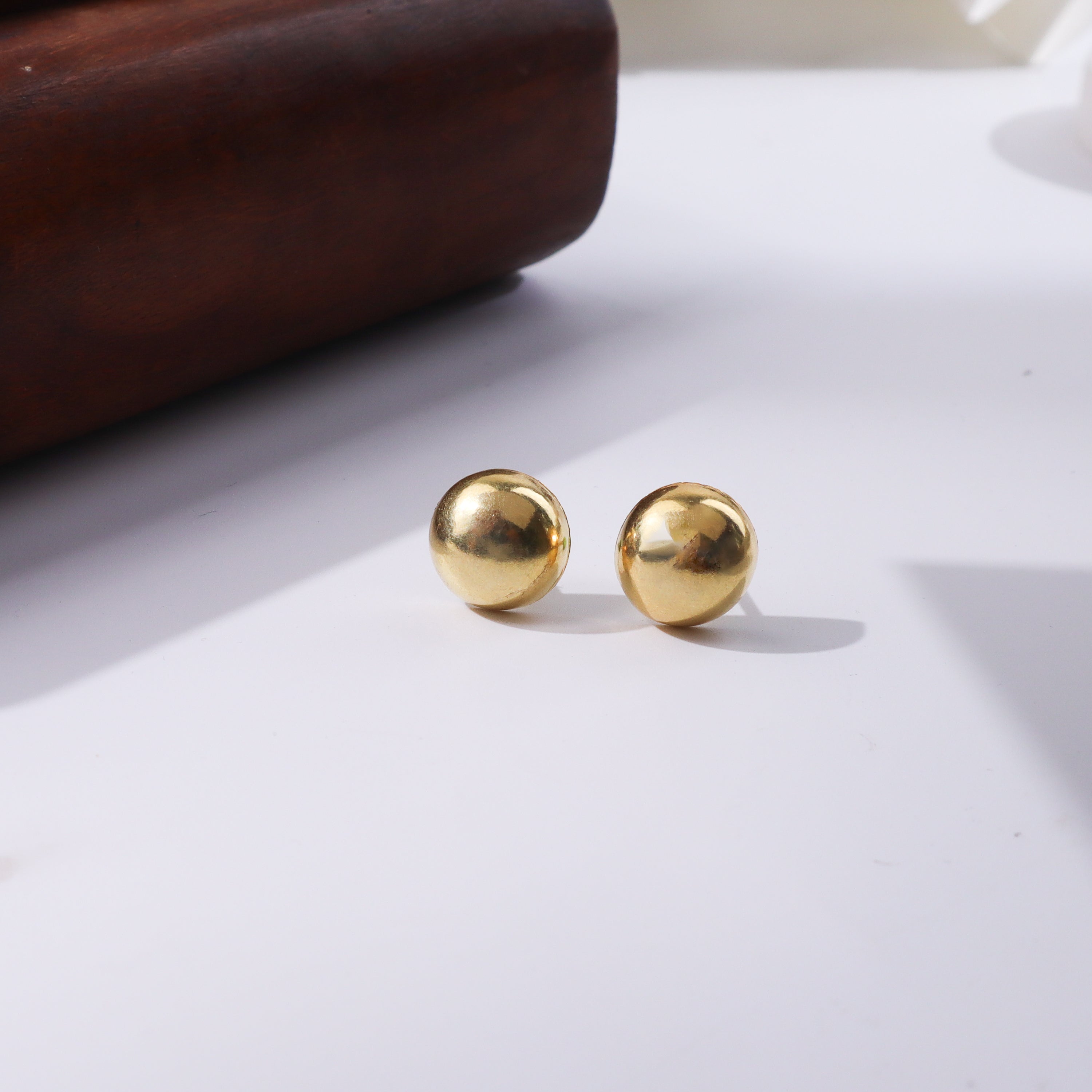 Gold spherical earrings on white background