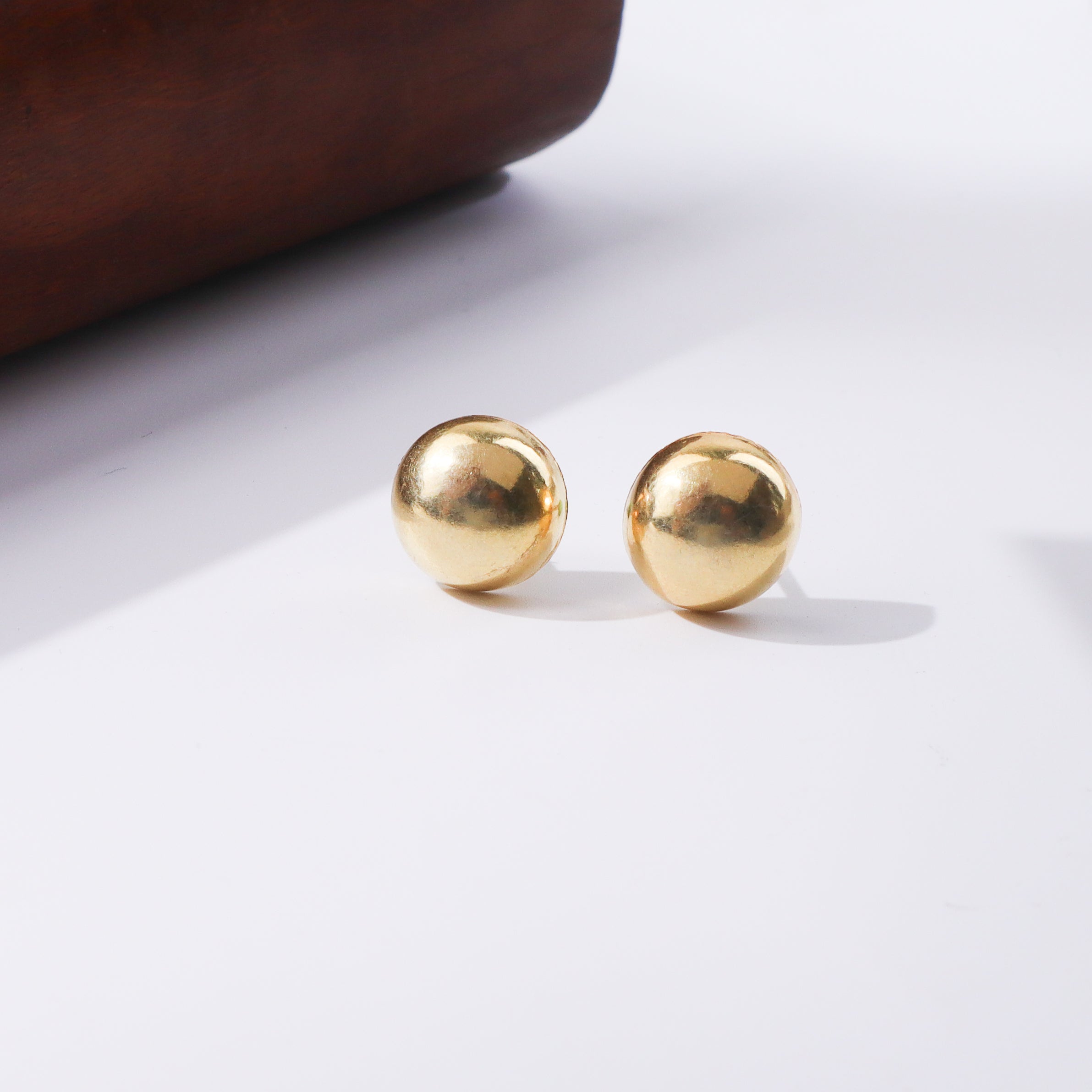 Gold spherical earrings on white background