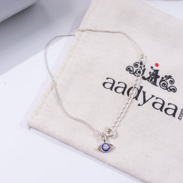 Silver evil eye bracelet with chain on beige fabric