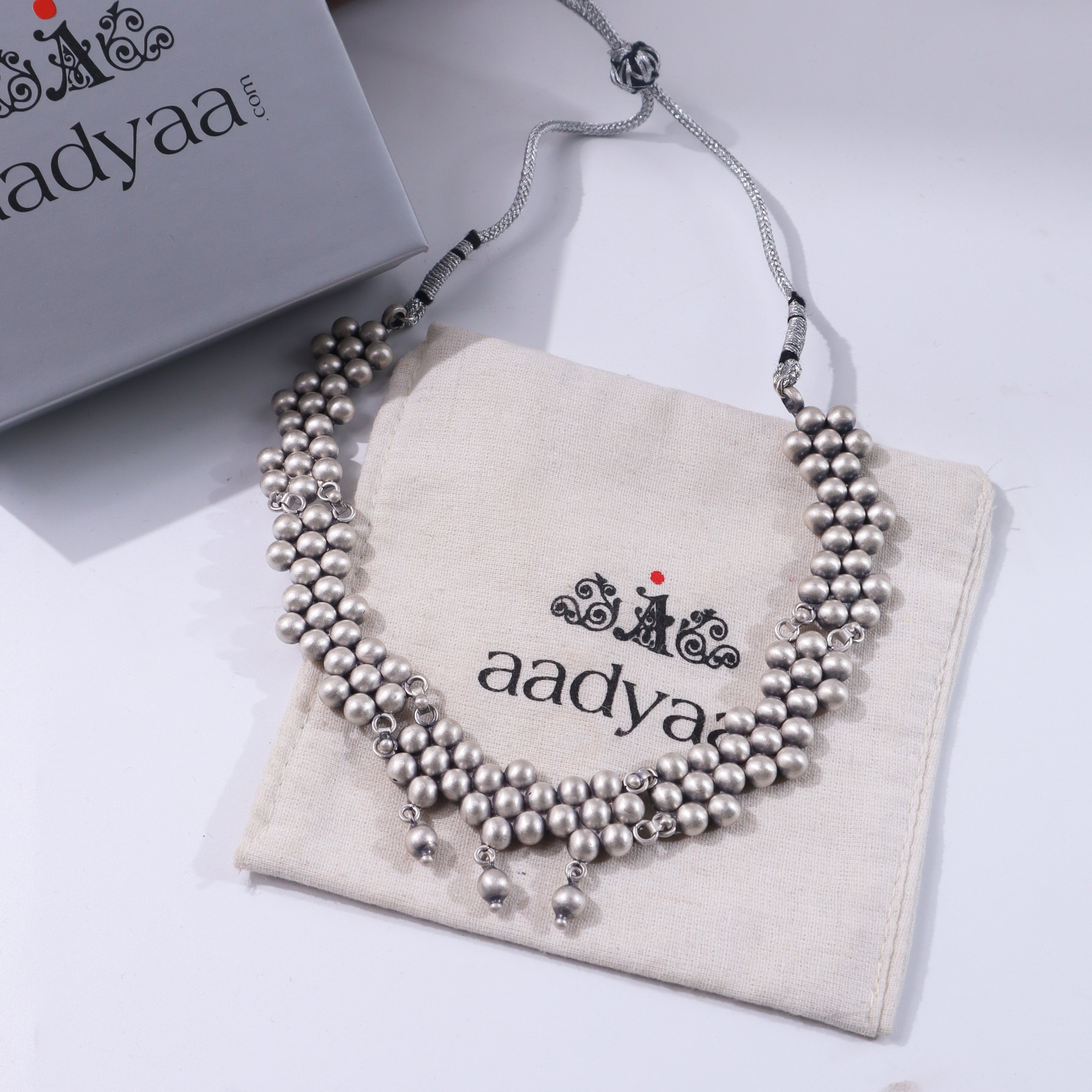Sterling silver beaded necklace with adjustable chain on beige fabric