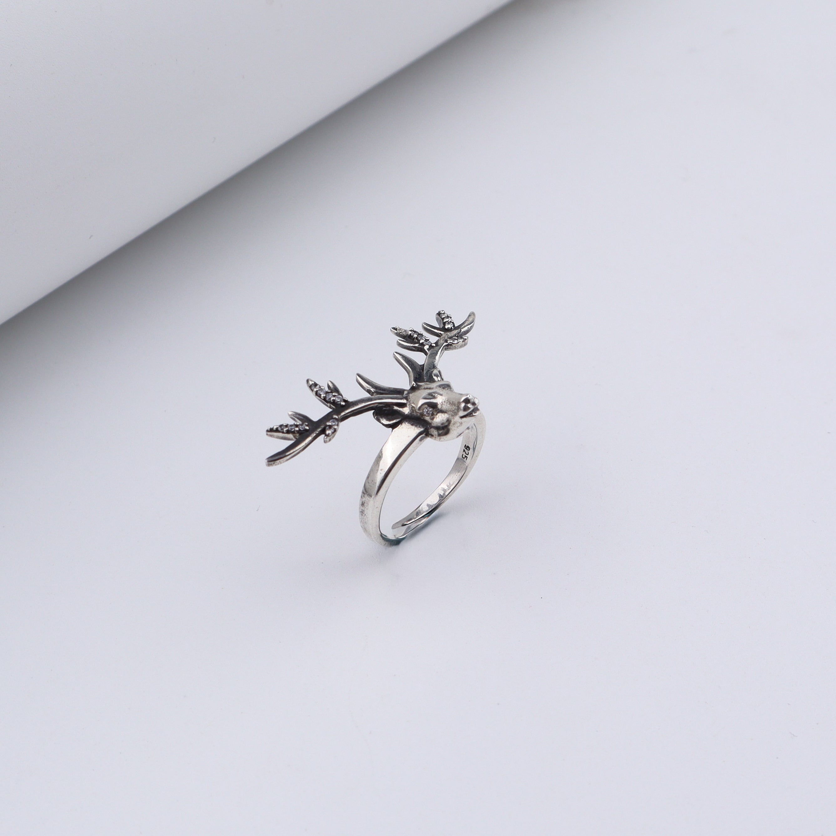 Silver deer ring with antler design and sparkling stones on white background