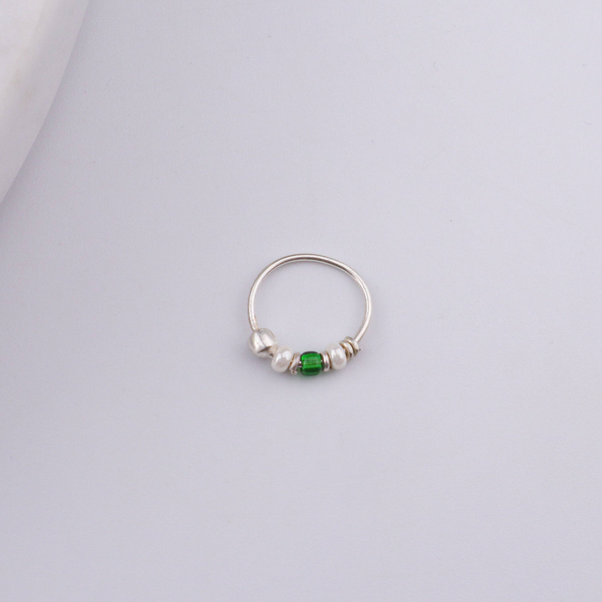 Angled view of Silver Septum Cum Nose Ring with green and white beads and a polished 92.5 sterling silver finish