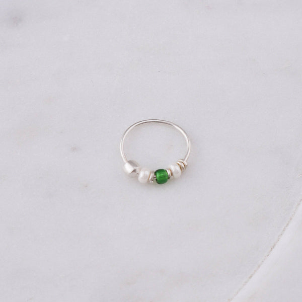 Flat-lay of Silver Septum Cum Nose Ring with Green & White Bead alongside traditional silver jewellery and accessories